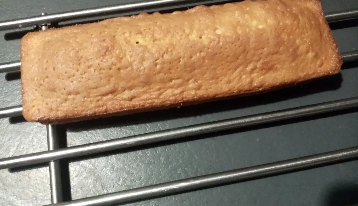 Une buche dorée, comme un biscuit madeleine, refroidit sur une grille.