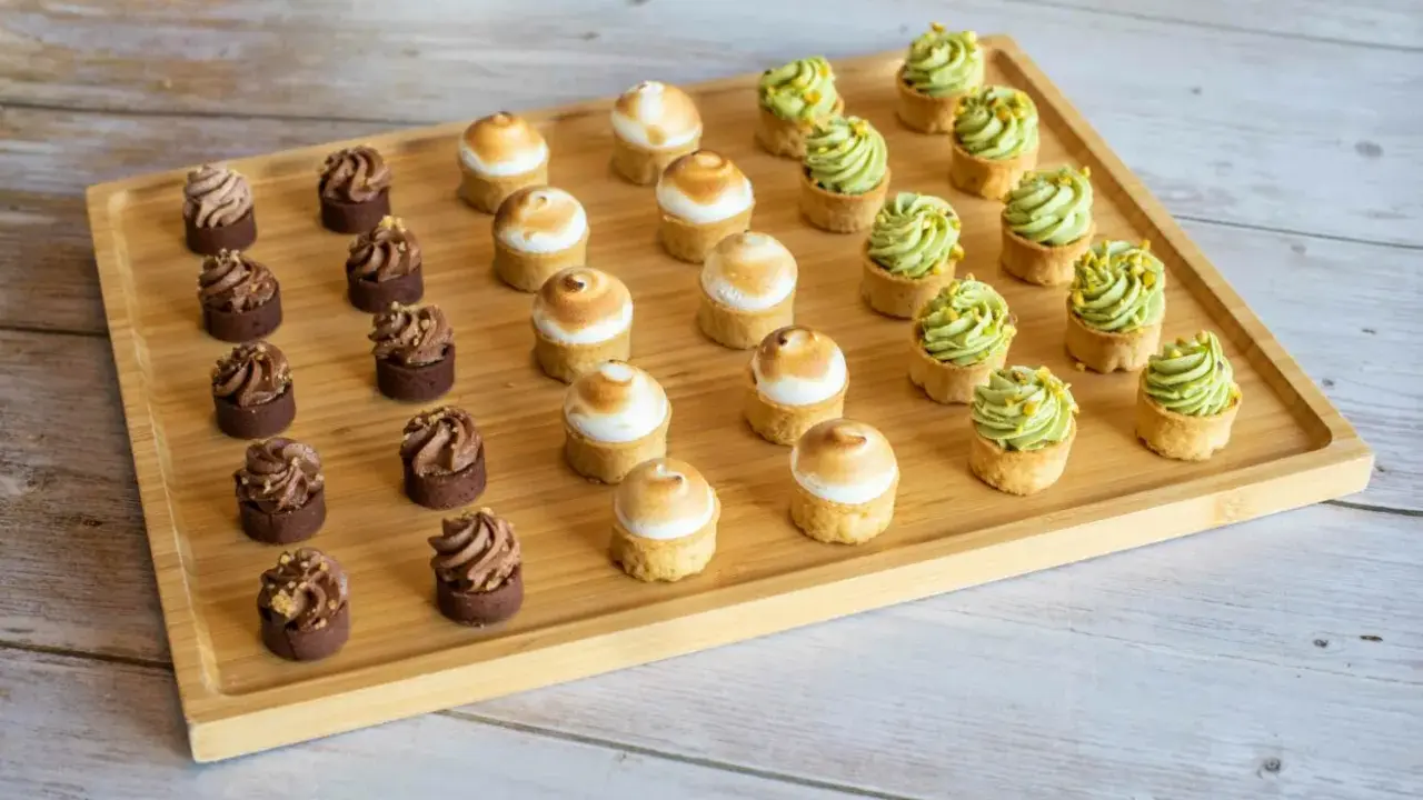 Plateau de mini tartelettes sucrées : chocolat, meringue et pistache. Un délice pour les yeux et les papilles.