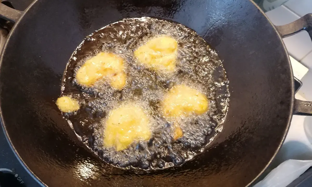 Des beignets de butternut dorent dans l'huile chaude d'une poêle.