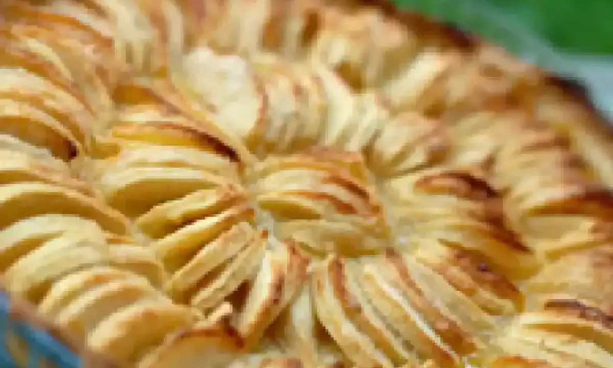 Tarte à la crème de grand-mère aux pommes finement tranchées, dorée et appétissante, prête à être dégustée.