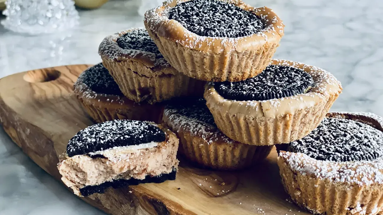 Une pile de petites bouchées sucrées faciles à faire, garnies d'un biscuit Oreo et saupoudrées de sucre glace. Parfaites pour une pause gourmande.