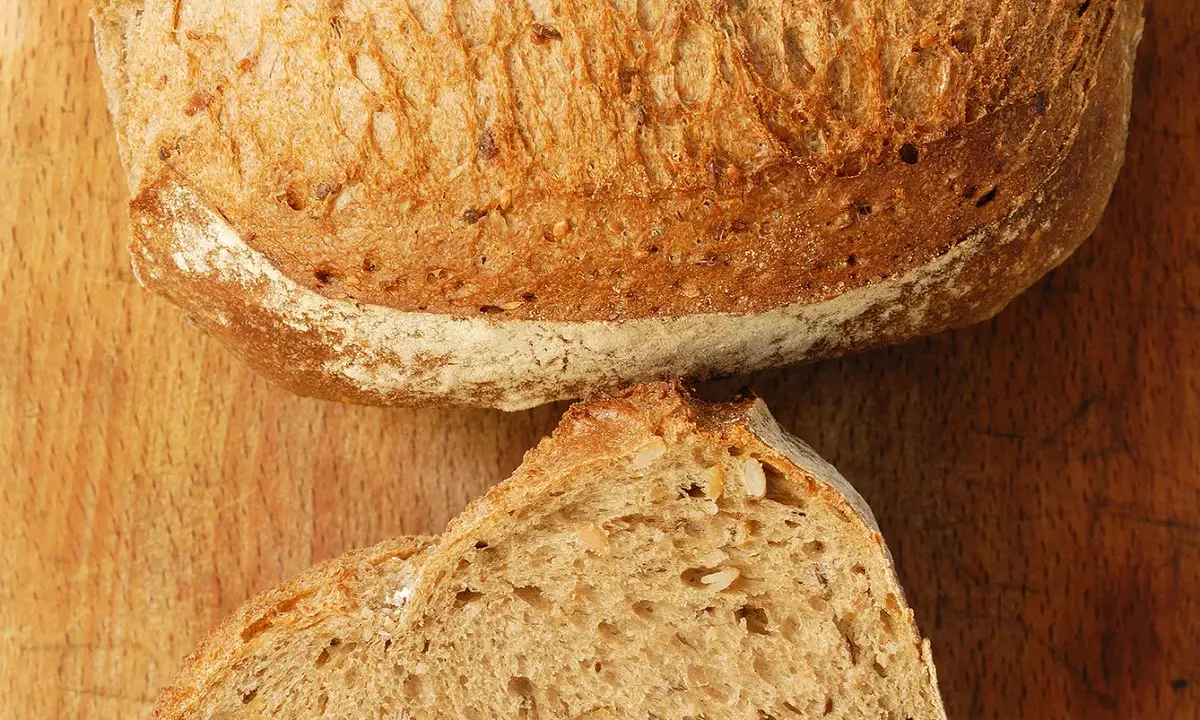 Un pain artisanal, doré et craquant, coupé en deux pour révéler sa mie aérée. La clé pour comment obtenir un pain très alvéolé réside dans sa texture.