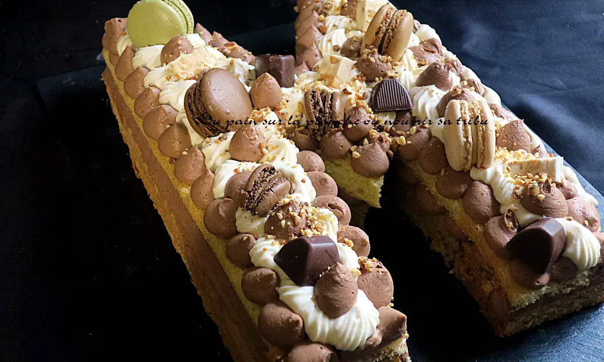 Un spectaculaire biscuit joconde number cake, orné de macarons, chocolat et crème, prêt à être dégusté.