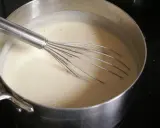 Une béchamel onctueuse se prépare dans une casserole avec un fouet. 1 litre de lait mijote doucement.