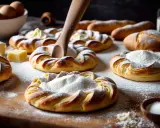 Pâte à croissant dorée, saupoudrée de sucre glace, prête à être garnie. Des ingrédients frais sur la table.