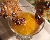 Délicieuse tuile de riz croustillante garnie de fruits secs, posée sur une tranche d'orange dans un verre.