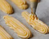 Pâte à choux traditionnelle dressée à la poche à douille sur une plaque de cuisson.