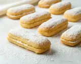 Une rangée de biscuits cuillère saupoudrés de sucre glace, prêts à être dégustés.