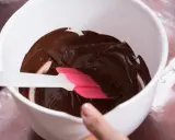 Comment faire fondre du chocolat : une spatule rose et blanche mélange du chocolat fondu brillant dans un bol blanc.