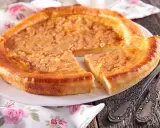 Une délicieuse tarte à la cassonade, dorée et appétissante, est servie sur une assiette blanche, prête à être dégustée avec des couverts ornés.