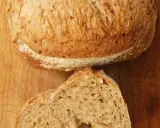 Un pain artisanal, doré et craquant, coupé en deux pour révéler sa mie aérée. La clé pour comment obtenir un pain très alvéolé réside dans sa texture.