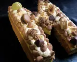 Un spectaculaire biscuit joconde number cake, orné de macarons, chocolat et crème, prêt à être dégusté.