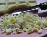 Comment râper du chocolat blanc : une barre de chocolat et des copeaux sur une assiette rose, avec un économe.