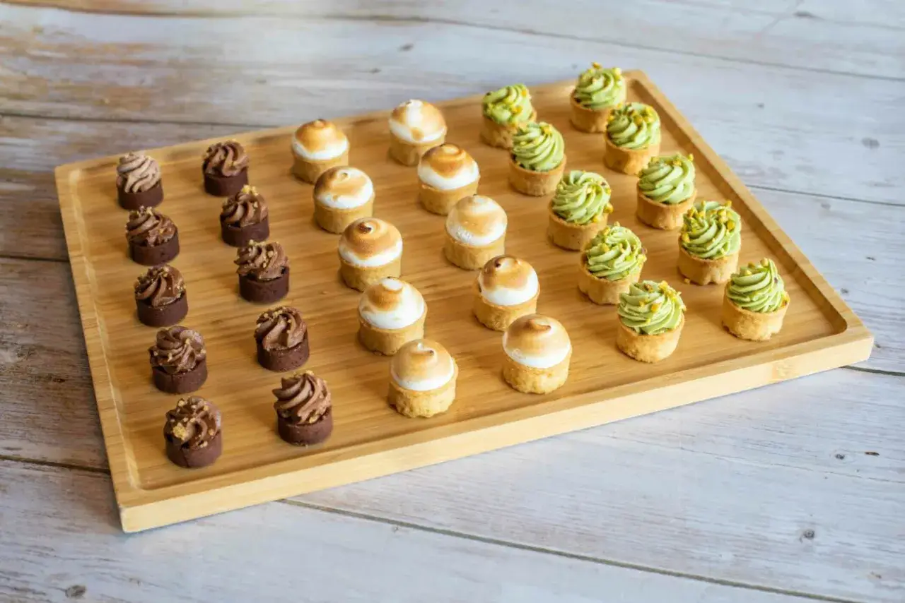 Plateau de mini tartelettes sucrées : chocolat, meringue et pistache. Un délice pour les yeux et les papilles.