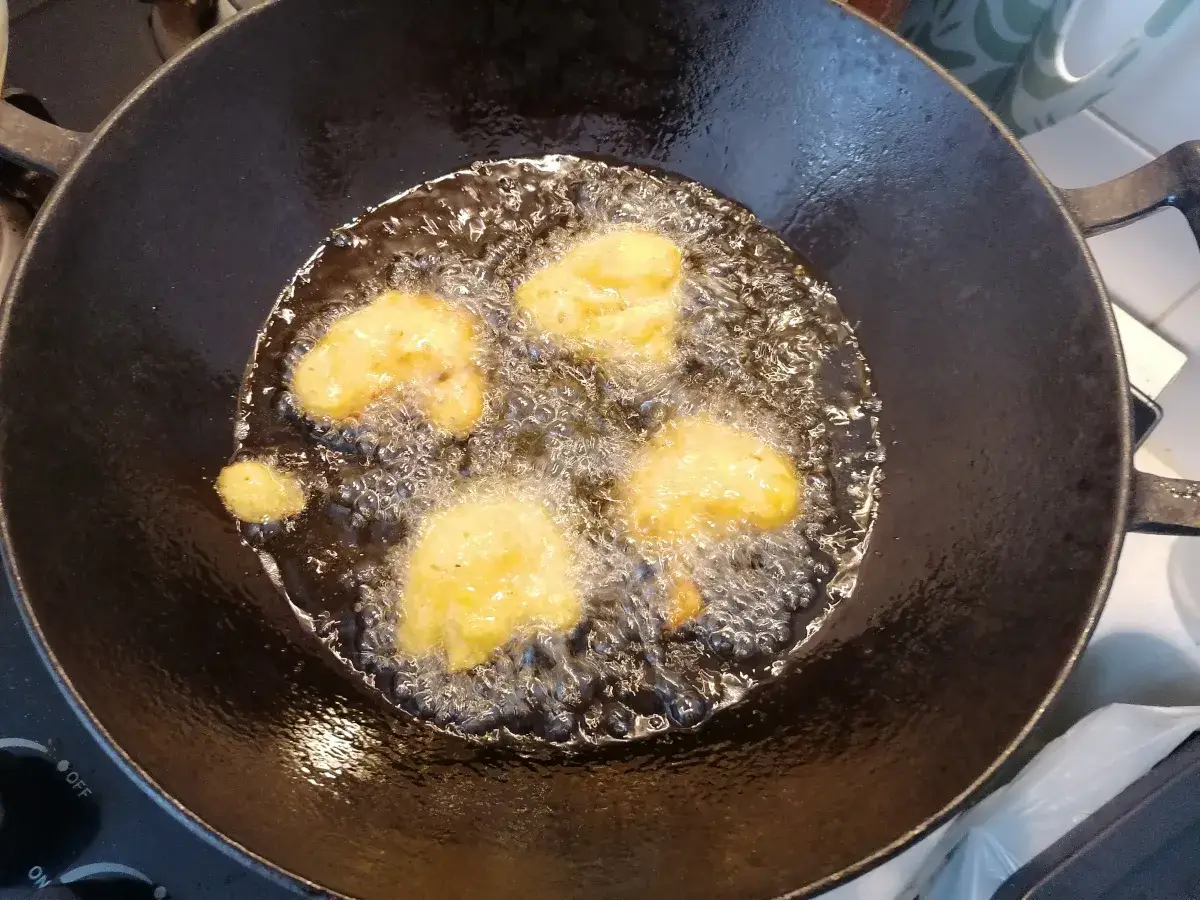 Des beignets de butternut dorent dans l'huile chaude d'une poêle.