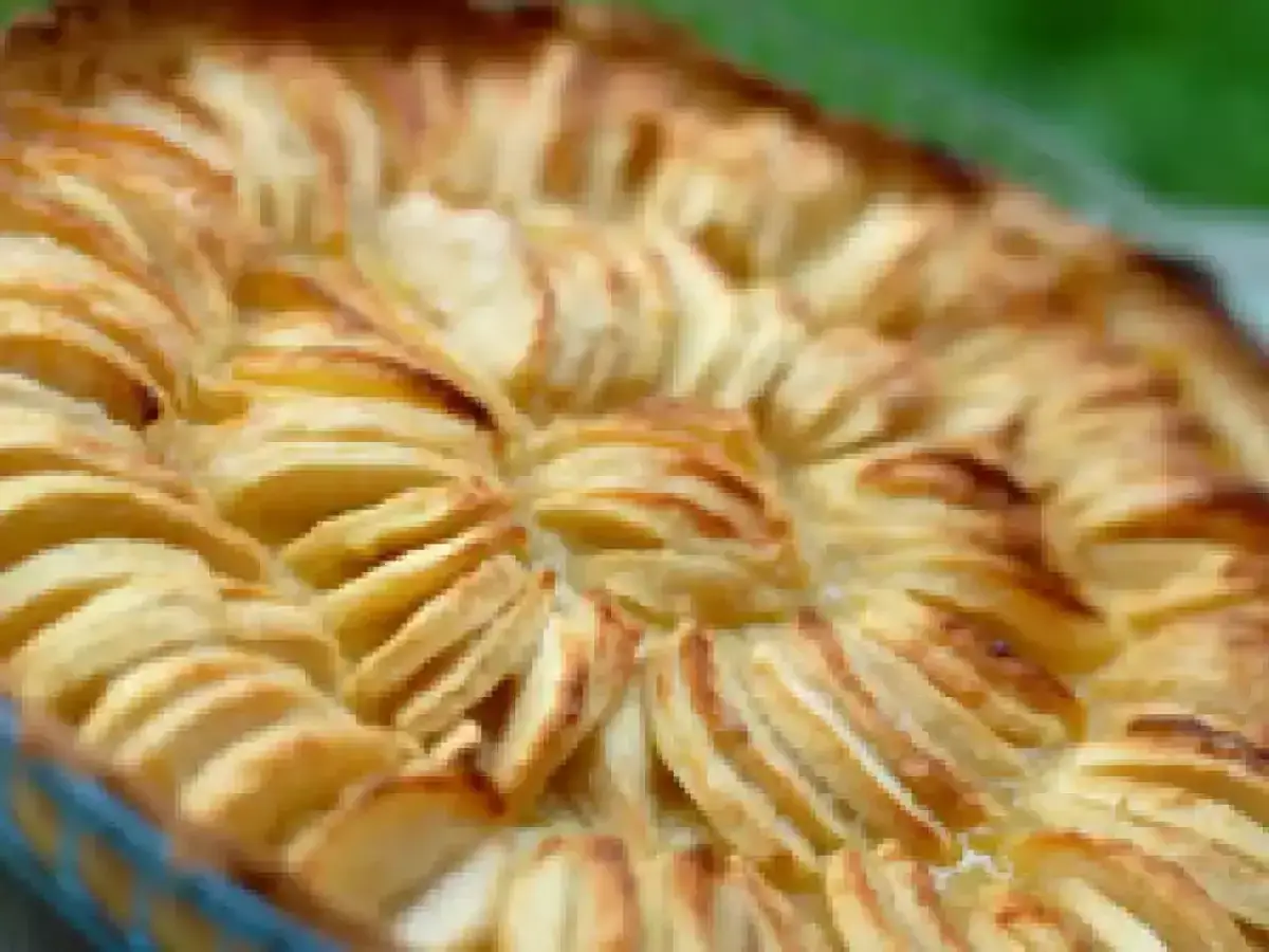 Tarte à la crème de grand-mère aux pommes finement tranchées, dorée et appétissante, prête à être dégustée.