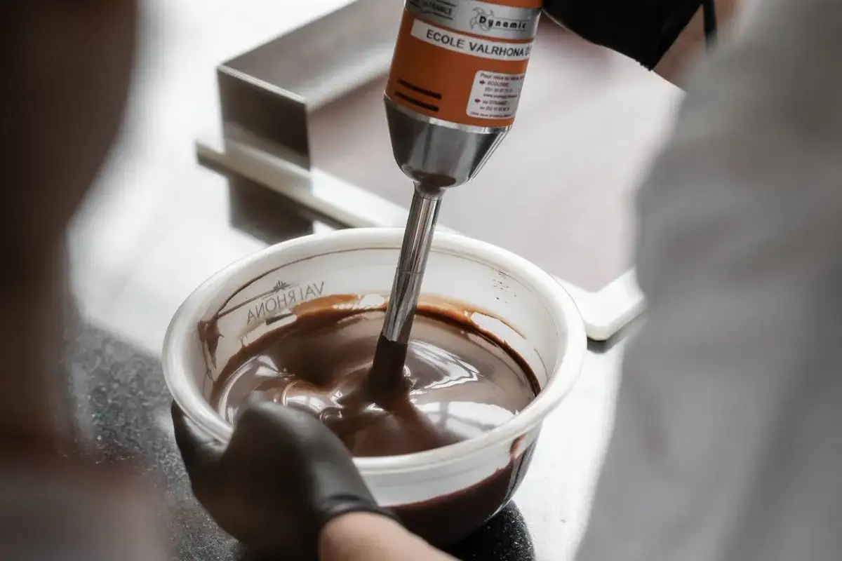 Un mixeur plongeant de l'École Valrhona lisse un chocolat, une technique pour comment rattraper un chocolat granuleux.
