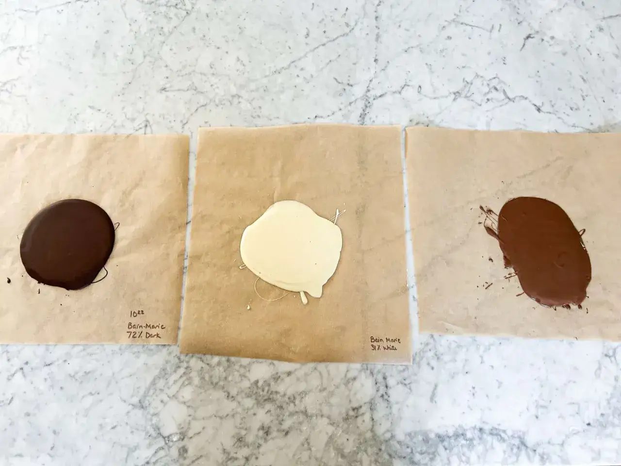 Trois chocolats fondus sur papier sulfurisé : noir, blanc et au lait. La méthode pour comment faire fondre le chocolat est illustrée.