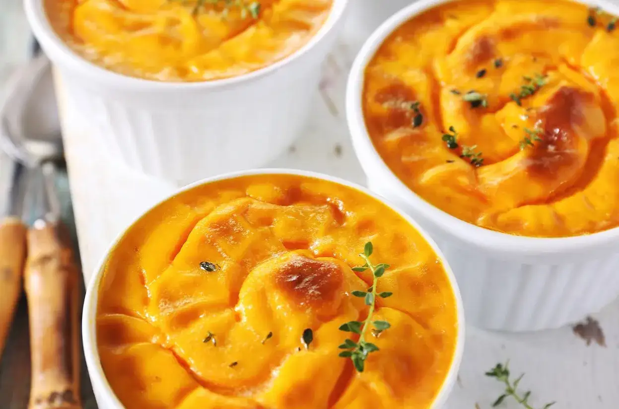 Trois ramequins de flan de butternut, dorés et garnis de thym frais. Un délice automnal.