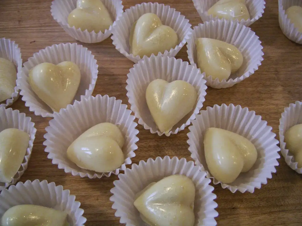 Douce courbe chocolat blanc en forme de cœur, disposée dans des caissettes en papier.