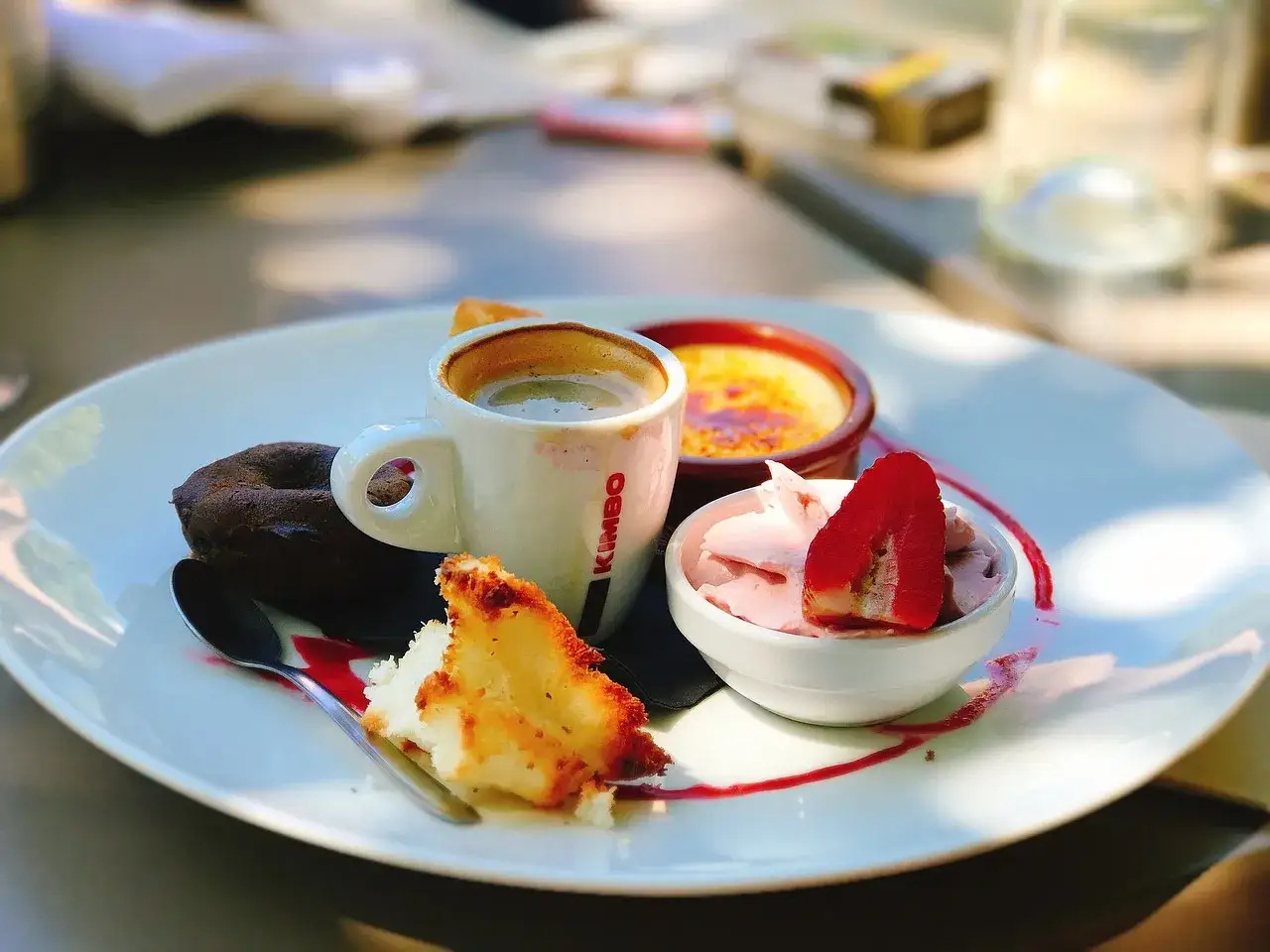 Assiette gourmande avec café, crème brûlée, mousse rose, gâteau au chocolat et une part de gâteau. Une petite bouchée sucrée facile à faire pour le plaisir.
