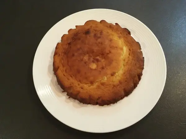 Un biscuit madeleine rond, doré et légèrement bombé, prêt à être transformé en un délicieux entremet.