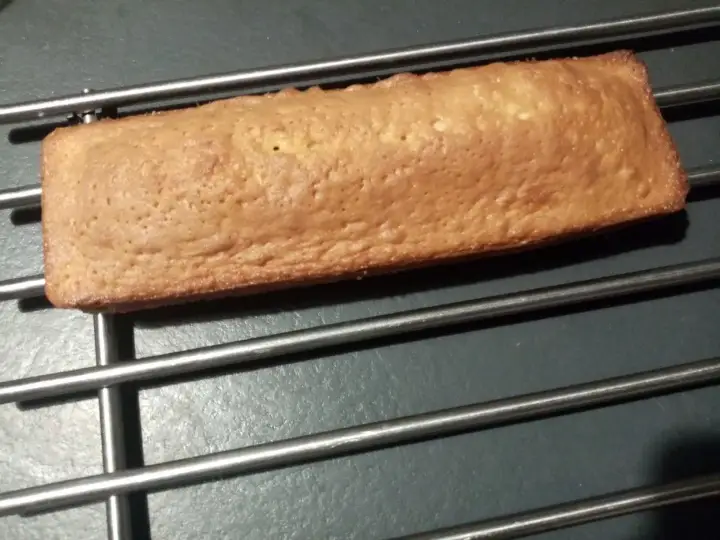Une buche dorée, comme un biscuit madeleine, refroidit sur une grille.