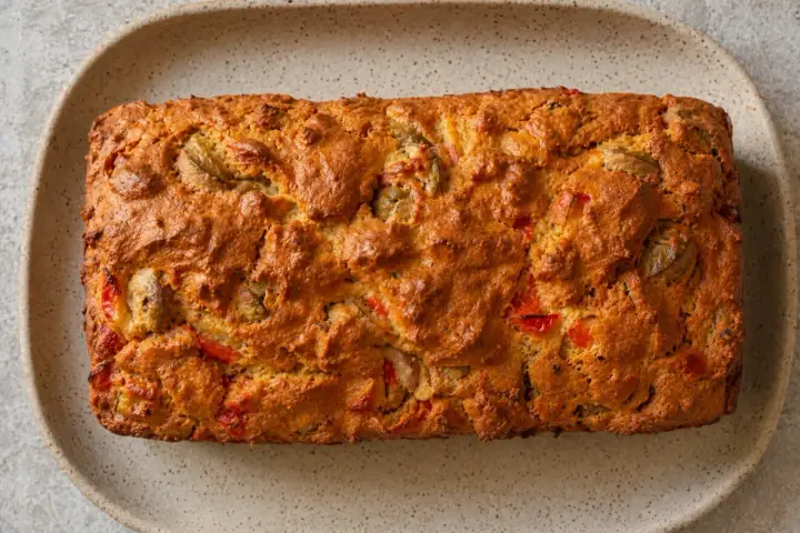 Un cake salé aux olives et poivrons rouges, une recette savoureuse qui rappelle un cake chèvre miel par sa texture dorée et ses saveurs.