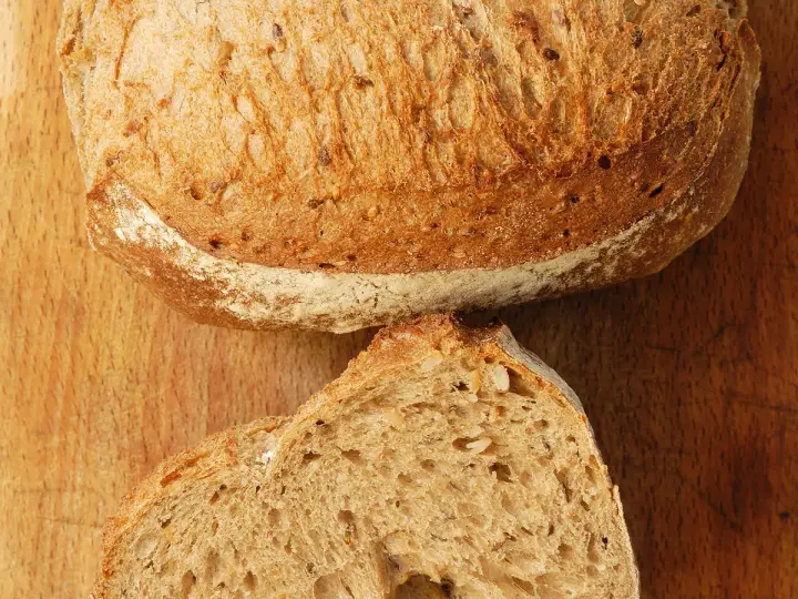 Un pain artisanal, doré et craquant, coupé en deux pour révéler sa mie aérée. La clé pour comment obtenir un pain très alvéolé réside dans sa texture.