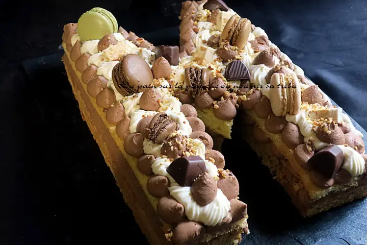 Un spectaculaire biscuit joconde number cake, orné de macarons, chocolat et crème, prêt à être dégusté.
