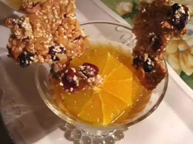 Délicieuse tuile de riz croustillante garnie de fruits secs, posée sur une tranche d'orange dans un verre.