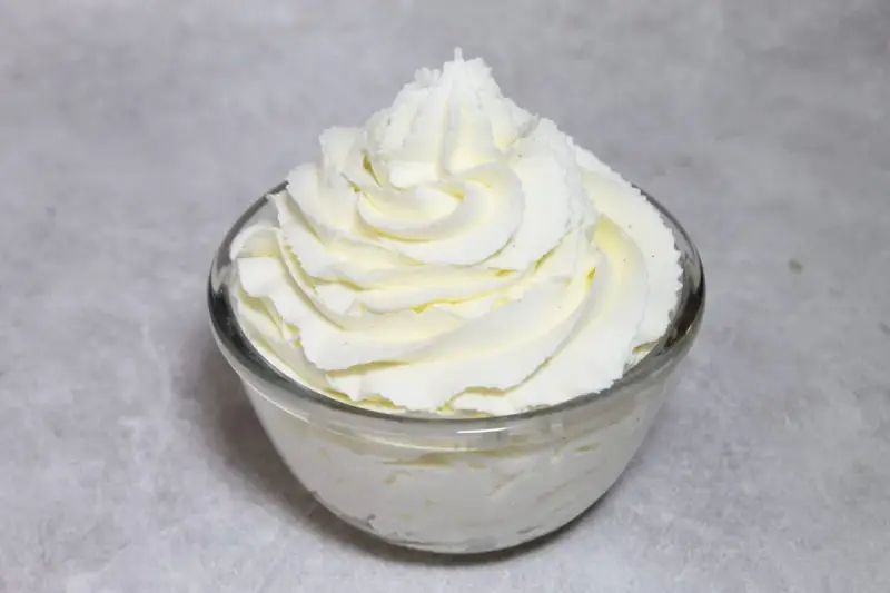 Chantilly au robot pâtissier, aérienne et onctueuse, dressée en rosace dans un bol en verre. Parfait pour garnir vos desserts.